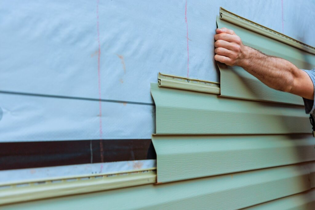 Installation of vinyl siding plastic panels on facade wall a new home by an contractor